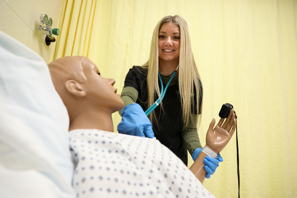 A female student taking a mannequin's pulse.