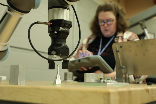 A female student cutting metal with machinery.