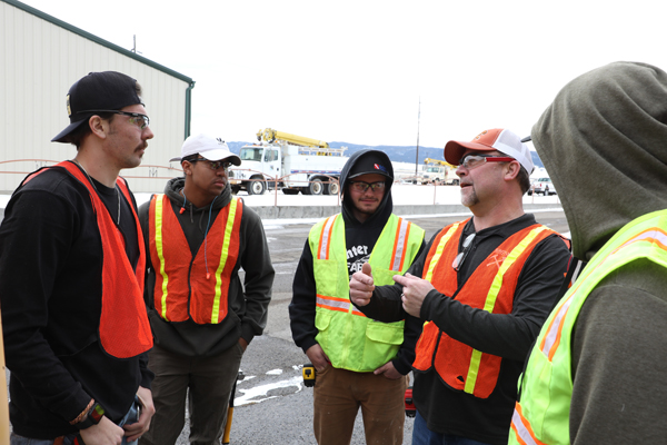 Group of men wearing high vision vests, standing in a circle