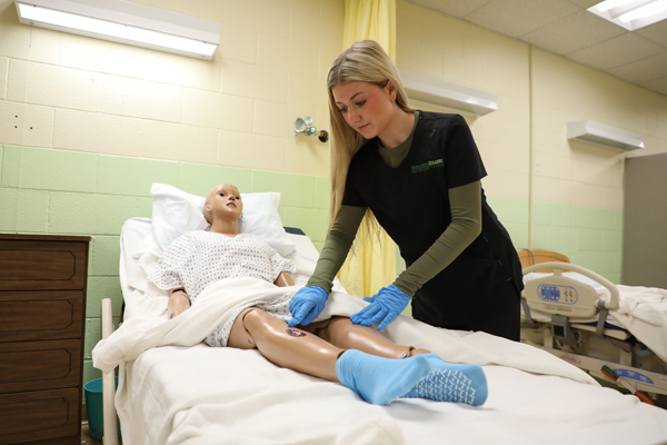 CNA student performing tests on a mannequin. 
