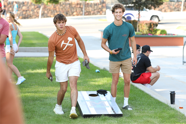 Two students playing cornhole on campus