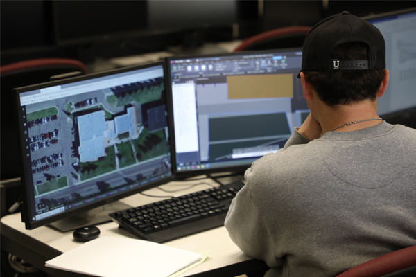 Man in a computer lab looking at two monitors