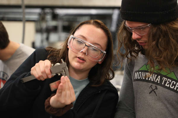 Two students measuring the thickness of a piece of metal