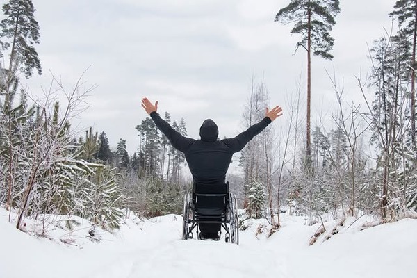 Wheel chair users in the snow with arms spread.