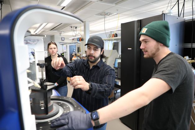 Three students using engineering lab equipment
