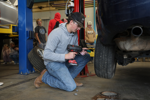 Male student installing a wheel on a car.