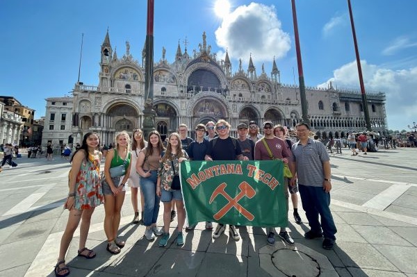 students hold Montana Tech flag in front of castle