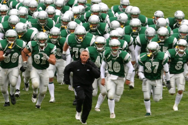 Coach Bob Green runs on the field with his players. 