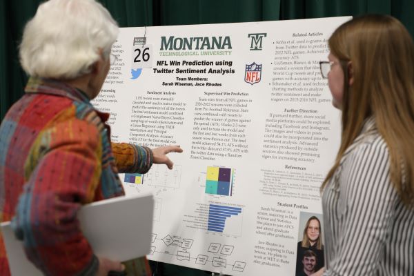 !Two people review an academic poster. 