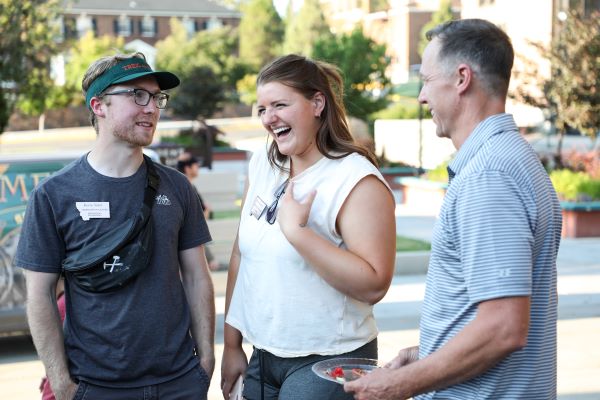 Two students laugh with Chancellor Cook