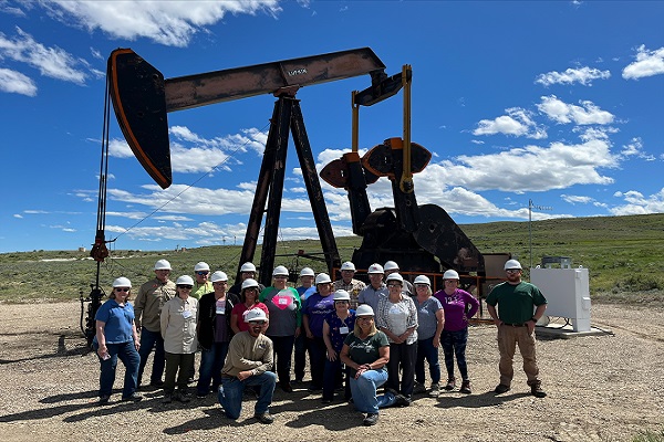 teachers in front of a pump jack