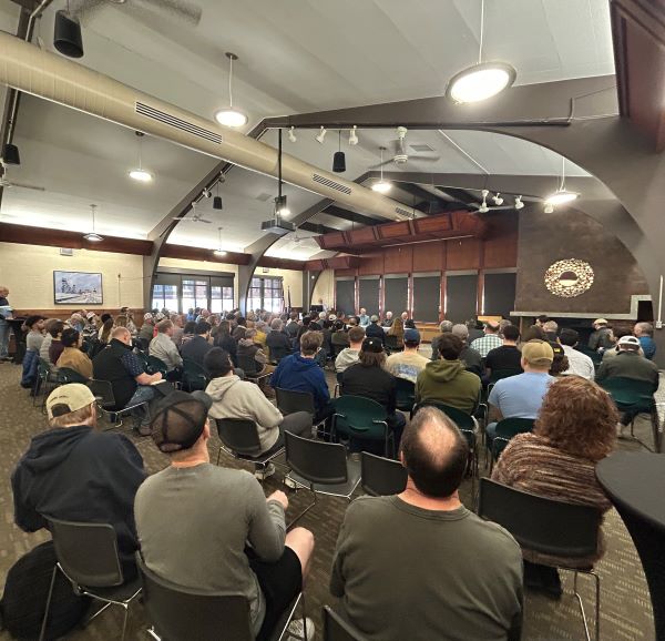 Dozens of people are seated listening to Ryan Lance, Richard Adkerson, and Bob Morris
