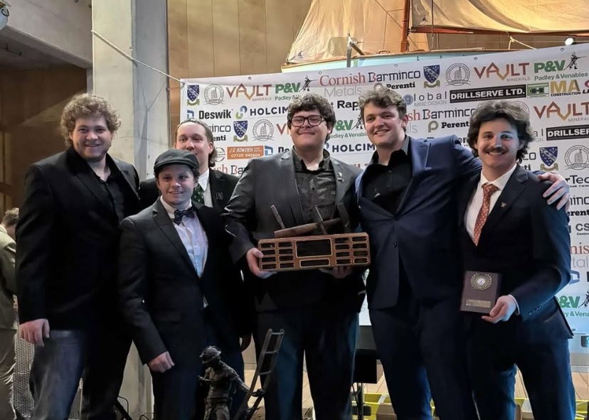 A group of male students pose with a trophy