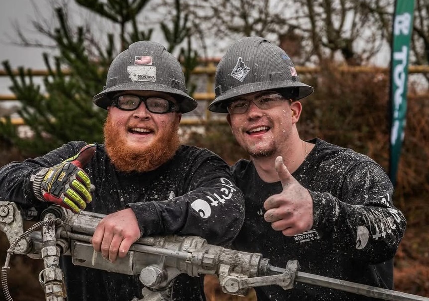 Two male students in mining gear, giving a thumbs up