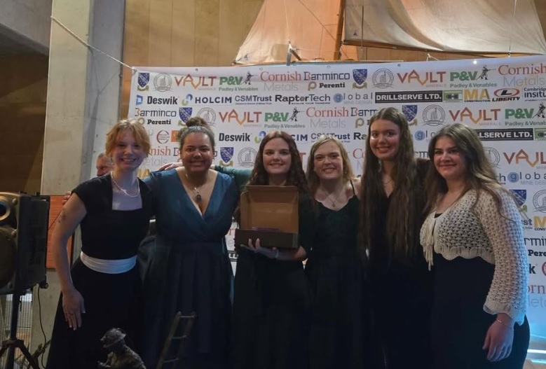 A group of female students pose with a trophy