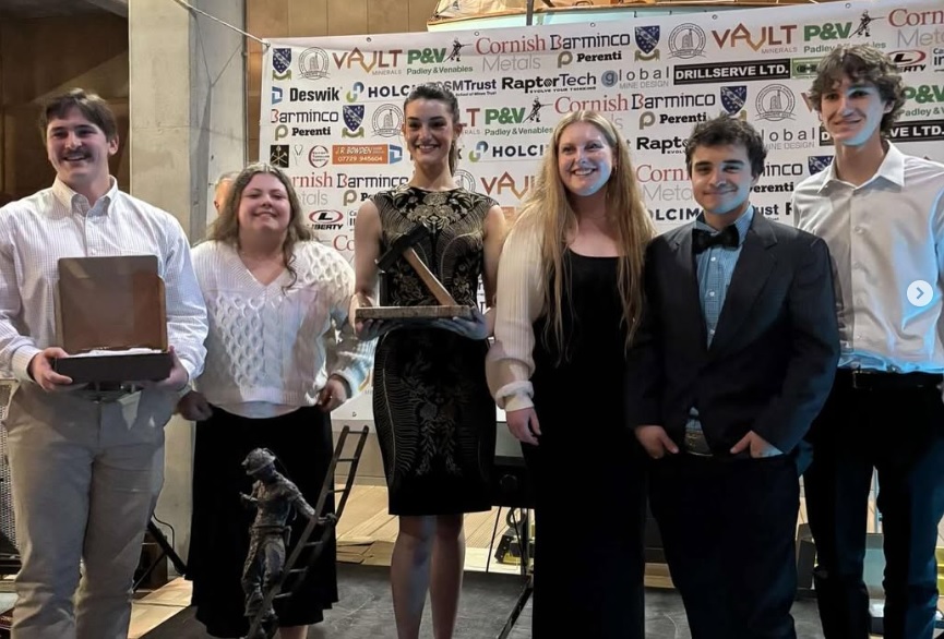 Male and female students stand with a trophy