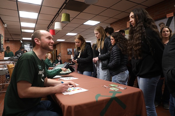 !Photo of admissions rep checking student into a registration table.