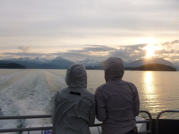 Two students on a boat looking at the mountains. 