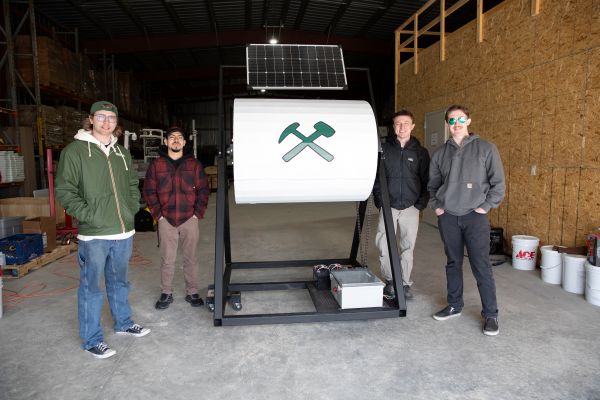 !Students stand with their solar-powered composter.