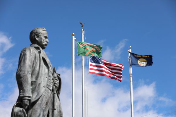 Marcus Daly statue with flags flying behind