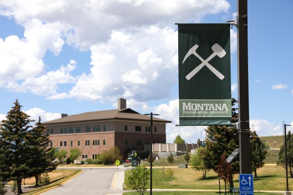 A Montana Tech flag on campus with a building in the background