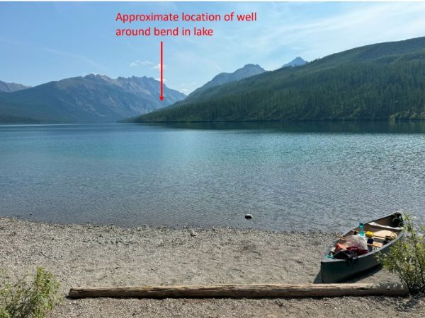 Kintla Lake well site photo with canoe in foreground. Text that says "Approximate location of well behind the lake" with arrow.