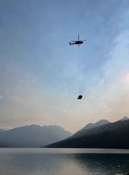 A helicopter lifts a load above Kintla Lake.
