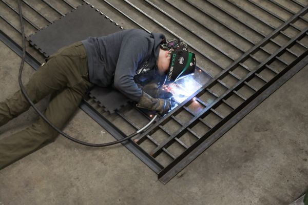 A welder works on a a metal fence