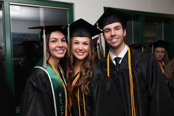 !Three students pose for a photo in their cap and gown